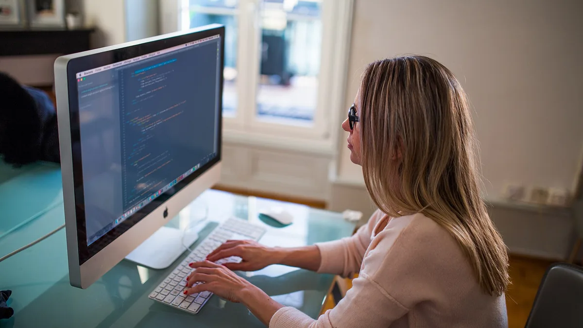 Seated Woman Typing on Apple Mighty Keyboard in Front of Turned-on Silver Imac